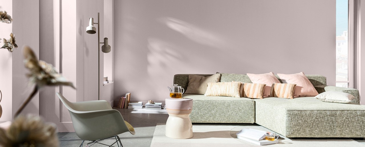 Wohnzimmer mit Wänden in sanftem Rosa und grauem Sofa